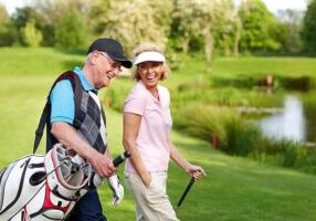 Image of a cheerful mature couple walking on a golf course together